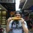 Mann isst gegrillten Maiskolben in Chinatown in Bangkok, Thailand