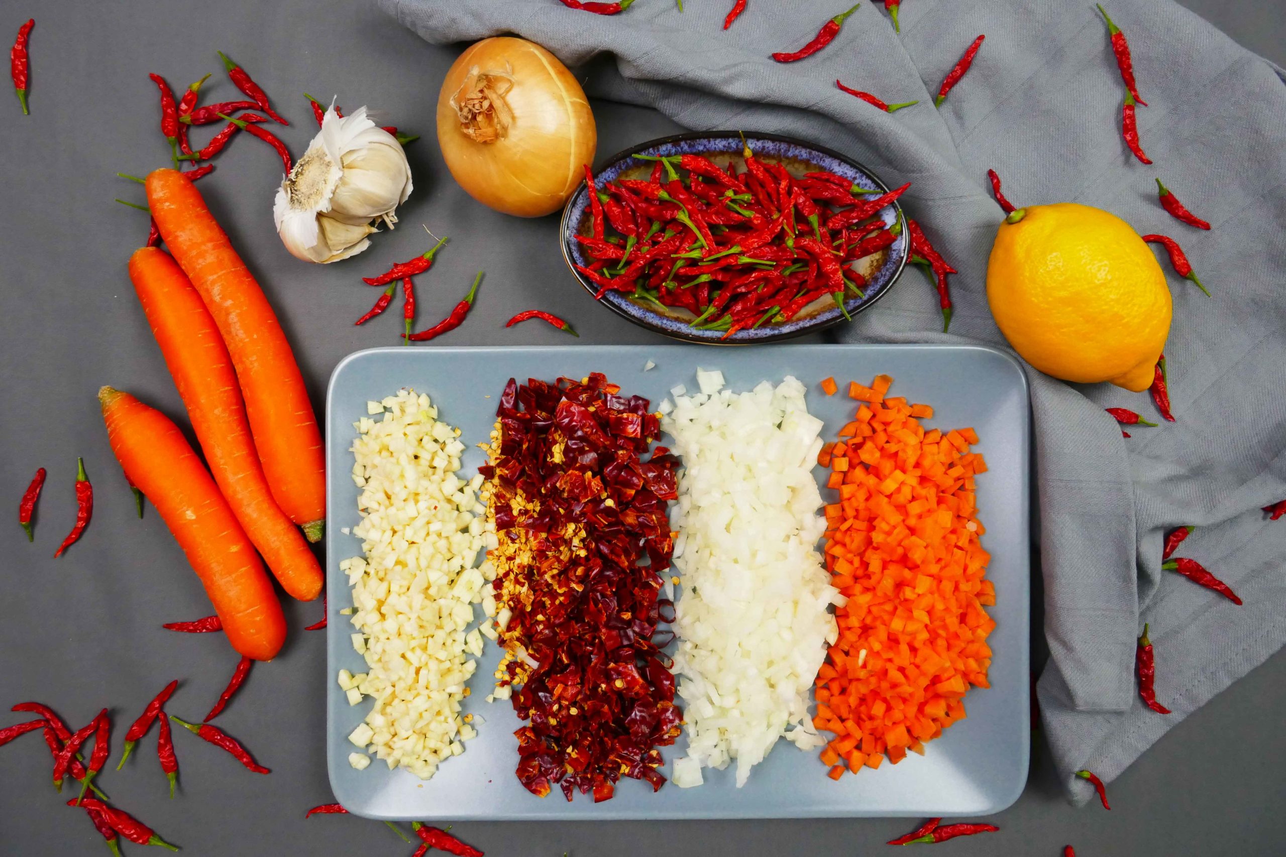 Geschnittene Zutaten für die vegane Tom Yam Chili Paste, Knoblauch, Chilischoten, Zwiebeln, Karotten, Zitrone