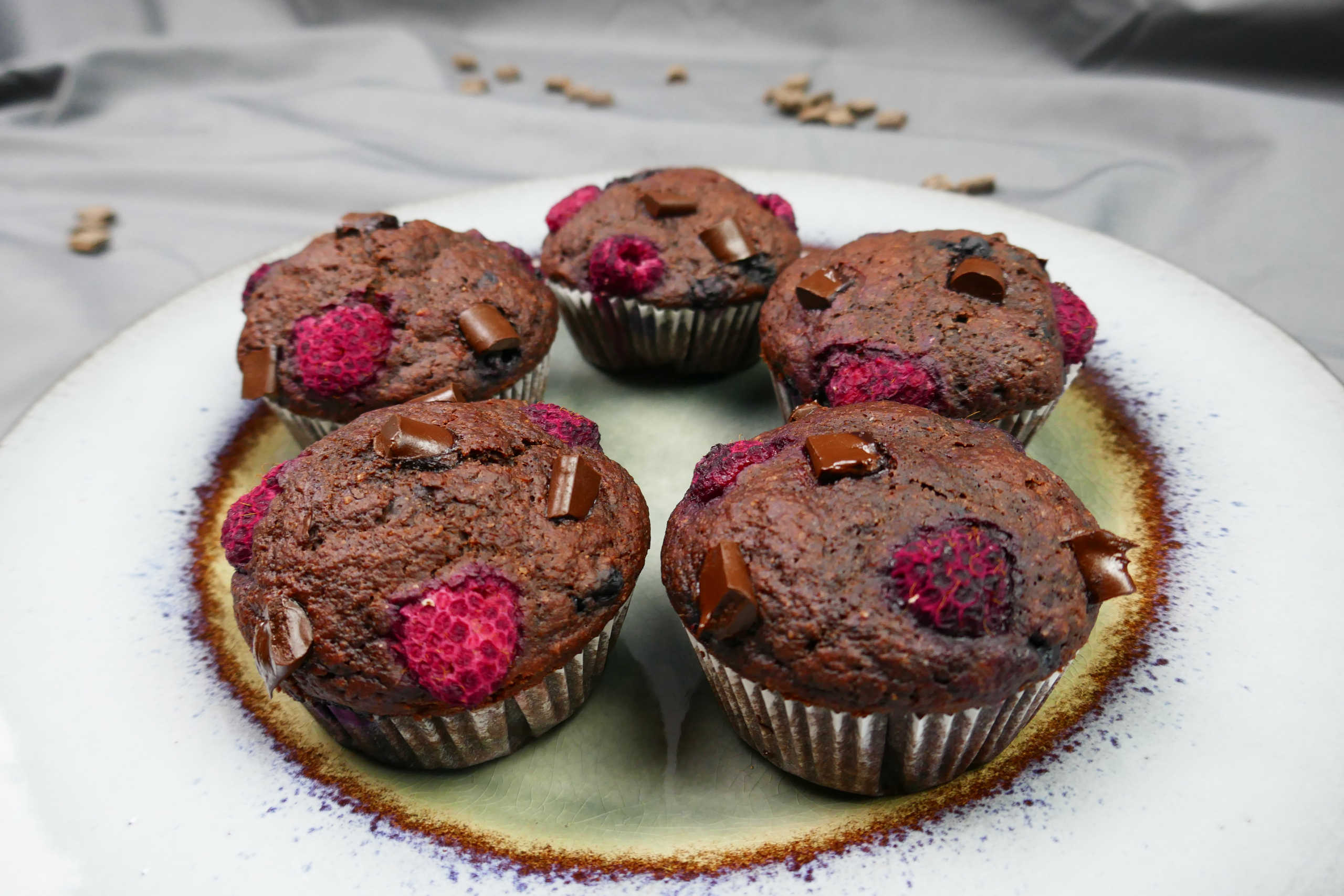 Vegane Schokomuffins mit Beeren, Himbeeren, Heidelbeeren und Schokostückchen auf einem Teller